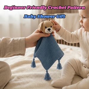 May include: A handmade crochet baby security blanket with a tan dog head and a blue square blanket with tassels. The text "Beginner Friendly Crochet Pattern" and "Baby Shower Gift" are displayed at the top of the image.