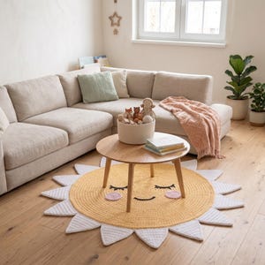 Puede incluir: Una alfombra amarilla y blanca con forma de sol y una cara sonriente sobre un suelo de madera. Una mesa de centro redonda de madera est&aacute; sobre la alfombra. Un sof&aacute; seccional beige, plantas y una cesta de mimbre est&aacute;n en el fondo.