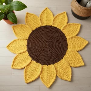 May include: A handmade, crochet sunflower rug with a brown center and yellow petals. The rug is circular, resembling a sunflower. The petals are evenly spaced around the center, creating a decorative floor covering. The rug is placed on a light-colored wooden floor.
