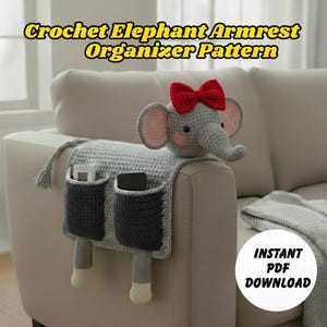以下が含まれることがあります： 赤いリボン、ピンクの耳、2つの濃い灰色のポケットが付いた、灰色の編み象のアームレストオーガナイザー。オーガナイザーはソファのアームに掛けるように設計されています。「Crochet Elephant Armrest Organizer Pattern」のテキストが表示されます。