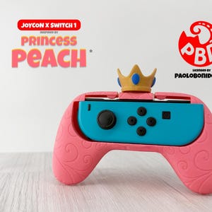 Puede incluir: Mando Joy-Con rosa para Nintendo Switch, inspirado en la Princesa Peach, con un accesorio de corona dorada. El mando tiene un centro turquesa y remolinos decorativos rosas. El texto incluye "JOYCON X SWITCH 1" y "PRINCESS PEACH".