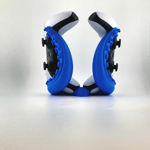 May include: A pair of white and black game controllers with blue, textured attachments. The controllers are positioned symmetrically against a white background, showcasing their design and features. The blue attachments have a unique, organic shape.