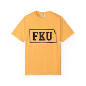May include: Mustard yellow t-shirt featuring the letters "FKU" in a black outlined rectangle. The short-sleeved crew neck shirt has the text centered on the front.