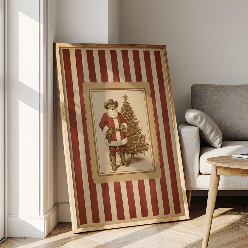 May include: Framed Christmas art print featuring a cowboy Santa Claus next to a decorated Christmas tree. The artwork is set against a background of red and cream vertical stripes, framed in wood.