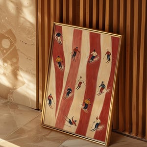 May include: A framed rectangular wall art print featuring a repeating pattern of vertical red and cream stripes. The artwork depicts eleven small figures of skiers in various colorful winter outfits, each using poles and skis on the striped background.