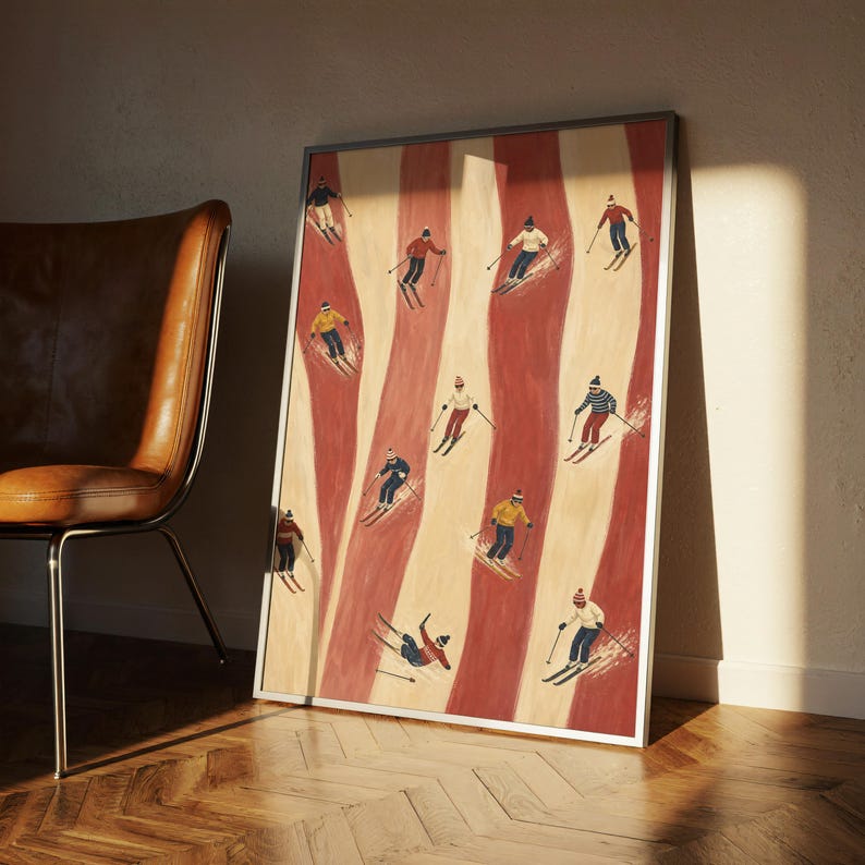 May include: A framed vertical art print featuring a repeating pattern of skiers in various colorful outfits descending down alternating vertical stripes of cream and terracotta red. The skiers are depicted in motion with poles and skis on a textured background.