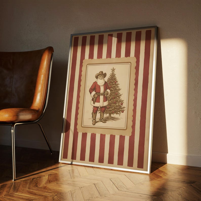 May include: Framed Christmas artwork featuring a vintage illustration of Santa Claus in a cowboy hat and boots, standing next to a decorated Christmas tree. The frame has a red and beige striped background.