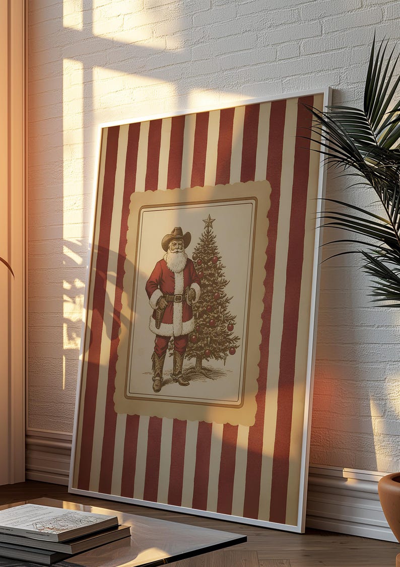 May include: Framed print featuring a cowboy Santa Claus illustration. The artwork depicts Santa in a red suit and cowboy hat, standing next to a decorated Christmas tree. The frame has a striped red and beige pattern, suitable for holiday decor.