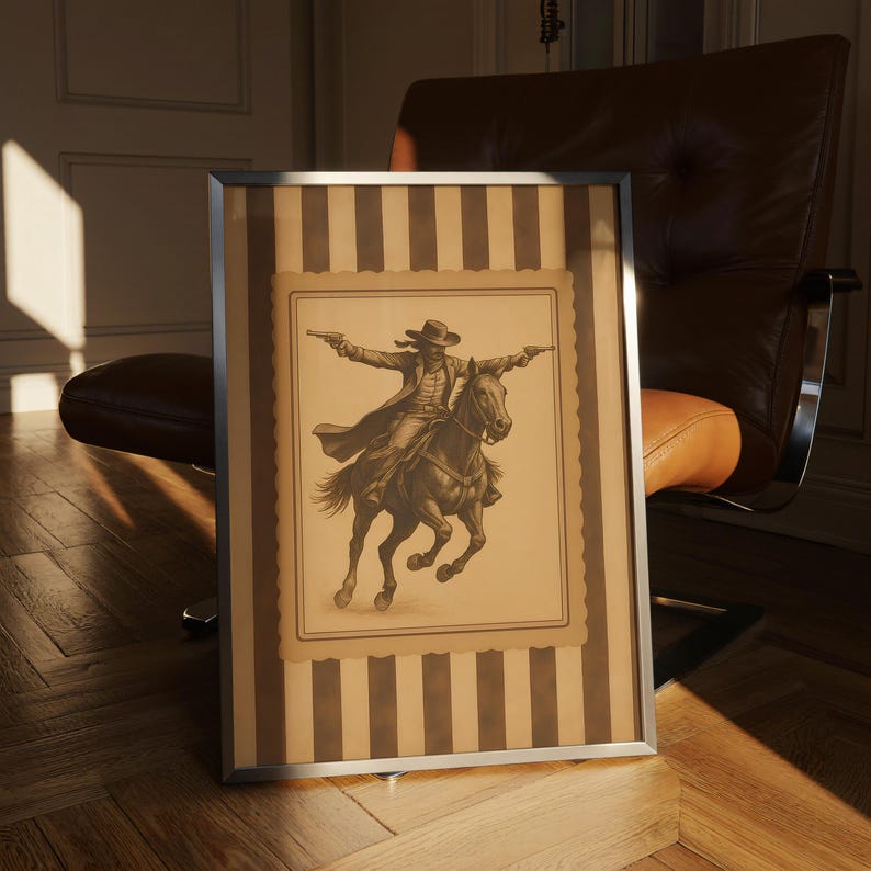 May include: Framed sepia-toned print of a cowboy on horseback, arms outstretched, holding two guns. The artwork is set against a striped background within a silver frame. The image evokes a classic Western theme.
