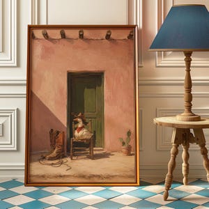 May include: A framed wall art print depicting a white duck wearing a brown cowboy hat and a red bandana, sitting on a small wooden chair in front of a green door on a pink adobe wall, with brown leather cowboy boots and a coiled rope nearby.