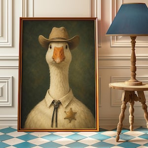 Pode incluir: Retrato emoldurado de um ganso usando um chapéu de cowboy, distintivo de xerife e camisa com gola. O ganso tem um corpo branco, um bico laranja e está sobre um fundo verde escuro. A moldura é dourada.