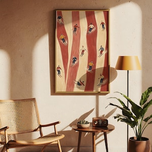 May include: A framed vertical wall art print featuring a stylized illustration of multiple skiers on a slope with alternating vertical stripes of cream and red. The skiers are depicted in various colorful outfits, including red, yellow, blue, and white, while navigating the snowy terrain.