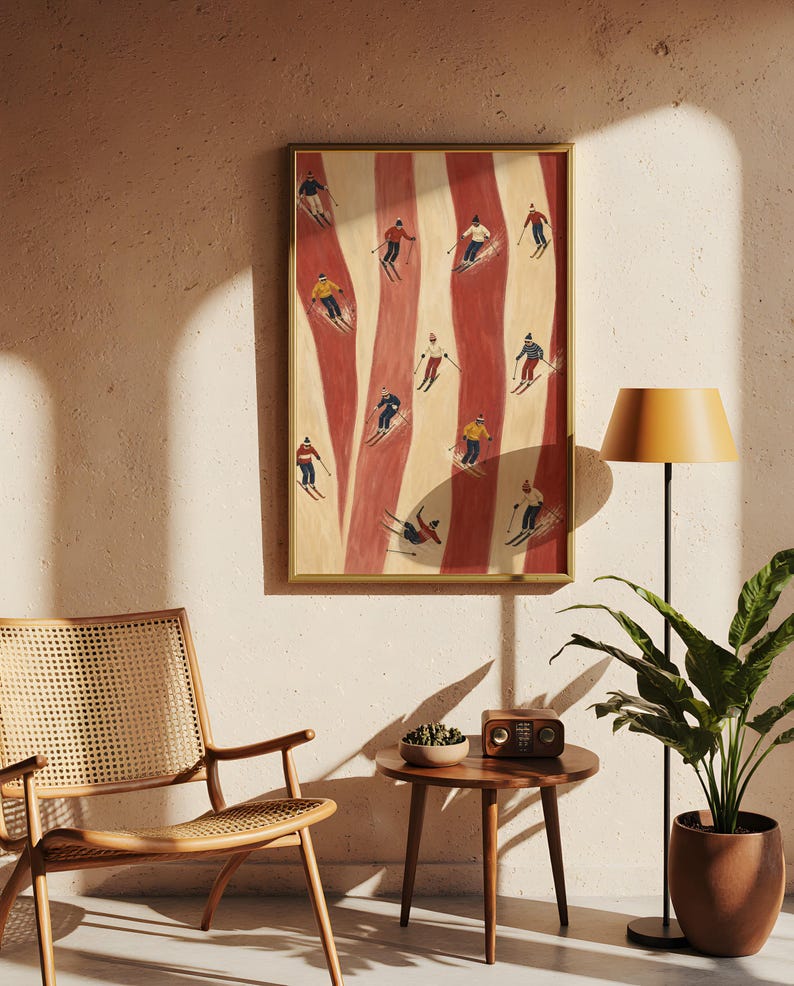 May include: A framed vertical wall art print featuring a stylized illustration of multiple skiers on a slope with alternating vertical stripes of cream and red. The skiers are depicted in various colorful outfits, including red, yellow, blue, and white, while navigating the snowy terrain.