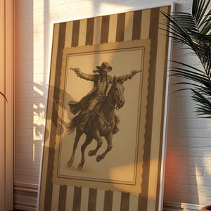 May include: A framed sepia-toned print of a cowboy on horseback, guns drawn. The artwork is set against a striped background with a white border. The image evokes a classic Western theme, suitable for home decor.