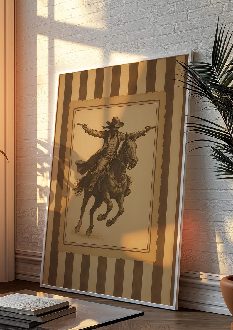 May include: A framed sepia-toned print of a cowboy on horseback, guns drawn. The artwork is set against a striped background with a white border. The image evokes a classic Western theme, suitable for home decor.