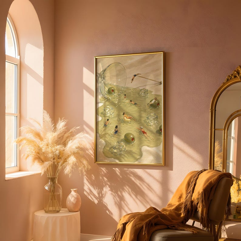 May include: A framed wall art print featuring a surreal illustration of people swimming in a spilled martini glass filled with liquid, ice cubes, and large green olives, all contained within a thin gold-colored metal frame.