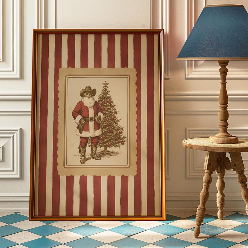 May include: Framed artwork featuring a cowboy Santa Claus illustration. The artwork is set against a red and white striped background, framed in gold. A Christmas tree is next to Santa. The artwork is displayed near a wooden lamp and table.