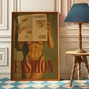 Peut inclure: Une œuvre d'art encadrée représentant une figure nue tenant un journal avec le mot "FASHION" imprimé dessus. La figure porte un bas imprimé léopard. Le mot "FASHION" est également imprimé en grandes lettres sur l'œuvre. Une cigarette allumée est tenue dans la main de la figure.