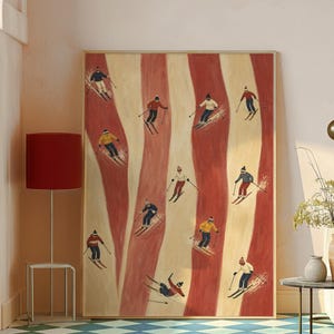 May include: A rectangular framed wall art print featuring a repeating pattern of vertical wavy red and cream stripes. The artwork depicts multiple small figures skiing in various poses, wearing colorful winter clothing, hats, and goggles.