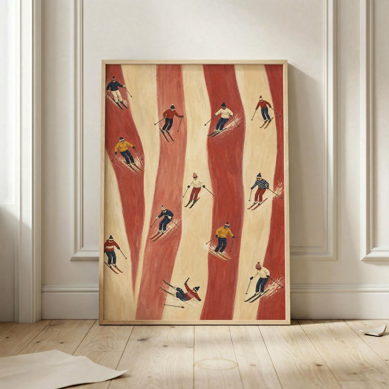 May include: A framed vertical art print featuring a repeating pattern of skiers on alternating cream and terracotta red vertical stripes. The skiers wear colorful winter clothing, including hats, jackets, and pants, while navigating the slopes.