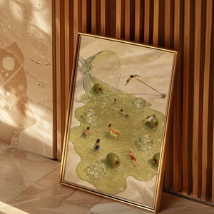 May include: A framed rectangular art print featuring a surreal illustration of a spilled martini glass. The liquid forms a pool containing small figures swimming, floating on green olives, and ice cubes, with a cocktail pick resting nearby.