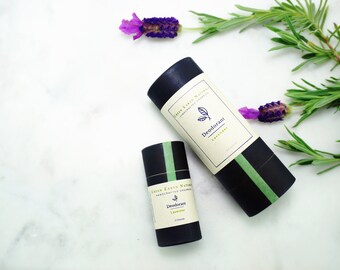 Może przedstawiać: Dwa czarne i zielone tubki dezodorantu z napisem "Green Earth Naturals Handcrafted Organic Deodorant Lavender" na etykiecie. Tubki leżą na białym marmurowym tle z kwiatami lawendy i zielonymi gałązkami rozmarynu.