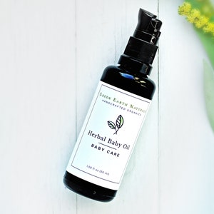 May include: A black glass bottle of Herbal Baby Oil with a black pump dispenser. The label reads "Green Earth Naturals, Handcrafted Organics" and "Herbal Baby Oil, Baby Care". The bottle contains 1.69 fl oz (50 ml) of oil.