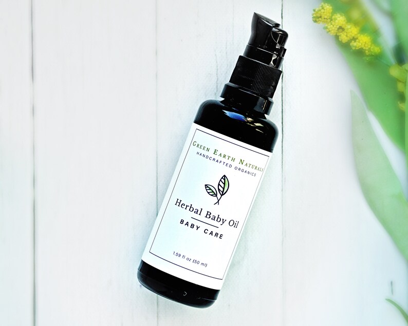 May include: A black glass bottle of Herbal Baby Oil with a black pump dispenser. The label reads "Green Earth Naturals, Handcrafted Organics" and "Herbal Baby Oil, Baby Care". The bottle contains 1.69 fl oz (50 ml) of oil.