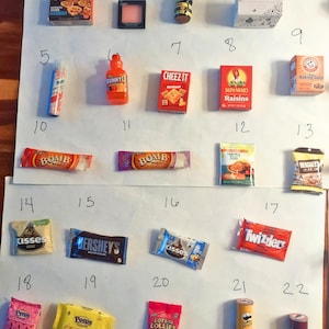 May include: A collection of miniature food items, including a box of potato skins, a bottle of SunnyD, Cheez-Its, Sun-Maid Raisins, Hershey's chocolate bar, Twizzlers, and Pringles. Other items include miniature Peeps and Kisses.