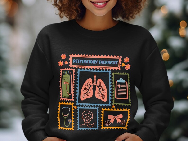 May include: Black sweatshirt with a colorful design featuring the text "RESPIRATORY THERAPIST" and illustrations of medical equipment and lungs. The design includes a stethoscope, oxygen tank, and a medical chart.