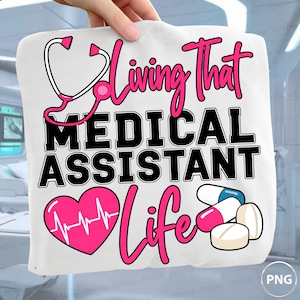 Puede incluir: Una superficie de tela blanca con un diseño gráfico que incluye un estetoscopio rosa, un corazón rosa con una línea de ECG y tres pastillas. El texto dice Living That MEDICAL ASSISTANT Life en letras negras y rosas con fuente estilizada.