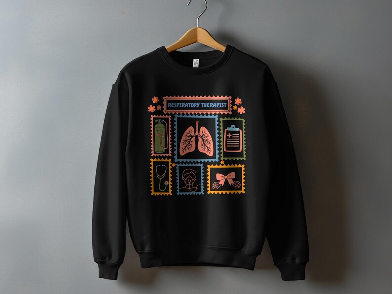 May include: Black sweatshirt with a colorful graphic design featuring medical-themed postage stamps. The stamps include images of lungs, a stethoscope, and the text "RESPIRATORY THERAPIST". The design is in shades of blue, orange, green, and yellow.