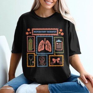 May include: Black t-shirt with a colorful graphic design featuring medical-themed postage stamps. The stamps include images of lungs, a stethoscope, and a medical chart. The text "RESPIRATORY THERAPIST" is displayed at the top.
