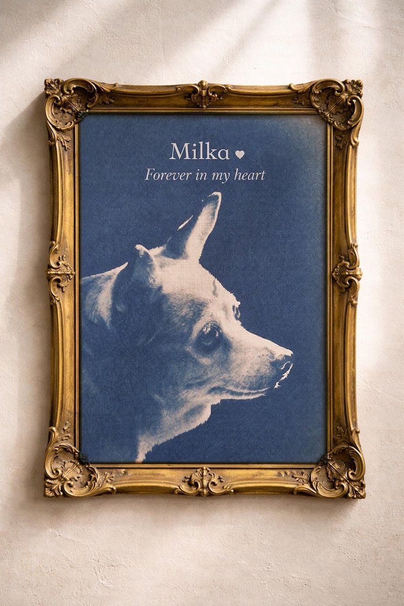 May include: A framed portrait of a dog named Milka, with the text "Forever in my heart." The dog is depicted in profile against a blue background, framed by an ornate gold-colored frame.
