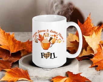 May include: White ceramic mug with the text "Autumn Leaves & Lattes Please" and "Fall" with a plaid heart design. The mug features a fall-themed design with a coffee cup, leaves, and steam. The mug is surrounded by orange and brown autumn leaves.