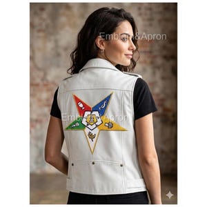 May include: A white leather vest with a colorful embroidered star design on the back. The star features various symbols in red, blue, green, yellow, and white. The vest has a collar, pockets, and the text "Emblem & Apron".