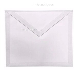May include: A white apron with a rectangular shape and a V-shaped top. The apron has a white border and a white strap. The text "Emblem&Apron" is printed on the apron.