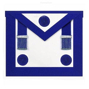 May include: A white apron with a blue border and details. The apron has a blue V-shaped top, two blue straps with silver and blue fringe, and three circular blue designs. The text "Emblem&Apron" is visible.