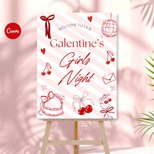 May include: A red and white sign on a wooden easel. The sign reads "Welcome to our Galentine's Girls Night" with decorative elements like hearts, cherries, and bows. The background has diagonal stripes.
