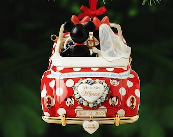 May include: A red and white polka-dot convertible car ornament featuring Mickey and Minnie Mouse figures. The back displays a heart-shaped plaque reading Mr. & Mrs. Mouse, a license plate with July 12, 2025, and a Just Married heart tag.