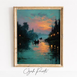 May include: Framed landscape painting depicting a serene river scene at dusk. The artwork features a vibrant sunset with orange and pink hues reflected in the water. Silhouetted trees and buildings line the riverbanks, with small boats on the water. The text "Ogah Prints" is at the bottom.