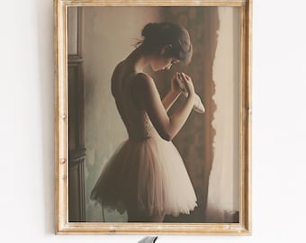 May include: A framed print featuring a ballerina in a soft pink tutu, holding a ballet shoe. The artwork has a vintage aesthetic with a warm color palette and is set in a gold-colored frame. The print is from "ogah prints".