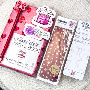 Peut inclure: Un livre emballé en rose avec des cœurs et des nœuds, des autocollants et un marque-page. Le livre est intitulé "Blind Date With A Book" et comprend un crayon et un marque-page avec un charme de clé. Des autocollants supplémentaires disent "Jingle Juice" et "In my Book Girl Era."