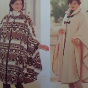 May include: Two capes are displayed. Cape B features a brown, white, and black geometric pattern with a front zipper. Cape A is a solid cream-colored cape with a high collar, dark brown toggle closures, and a decorative blanket-stitched edge.