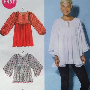May include: Sewing pattern featuring three different blouse designs. One blouse is red with dotted sleeves, another is floral with bell sleeves, and the third is white with a ruffled hem. The word "EASY" is in a pink circle in the upper left corner.