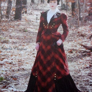 May include: A long-sleeved dress featuring a red and black chevron plaid pattern, a high white collar, and a black lapel. The bodice includes two rows of gold buttons, and the skirt has a black pleated hem. The text A B C and Angela Clayton appear.
