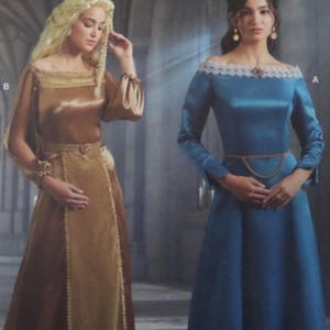 May include: Two long-sleeved floor-length dresses. The left dress is gold satin with a square neckline and lace trim. The right dress is blue satin with an off-the-shoulder white lace neckline and a gold chain belt. Both are labeled B and A.