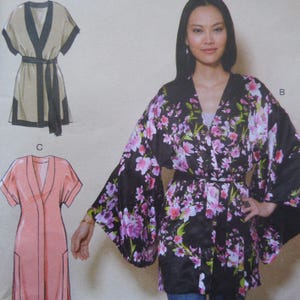 May include: A pattern for a kimono-style robe with a floral print in pink and purple on a black background. The robe has wide sleeves and a matching belt. Two additional robe patterns are shown in beige and pink.