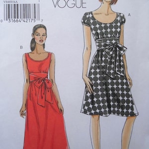 May include: Vogue pattern featuring two dress designs. One dress is red with a bow at the waist. The other dress is black and white with a polka dot pattern and a bow at the waist. The pattern includes the text "VOGUE" at the top.
