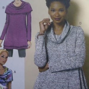 May include: A woman wearing a gray cowl neck sweater. The image also shows a drawing of a purple tunic with a cowl neck and long sleeves. The drawing is labeled with the letter "B".